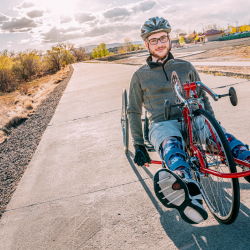 A man using an adaptive bike in parkland