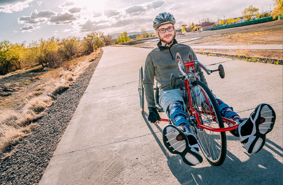 A man using an adaptive bike in parkland